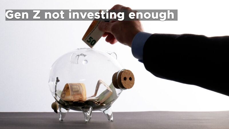 A photo of a transparent piggy bank with a few bills and coins in it sitting on a table. A...